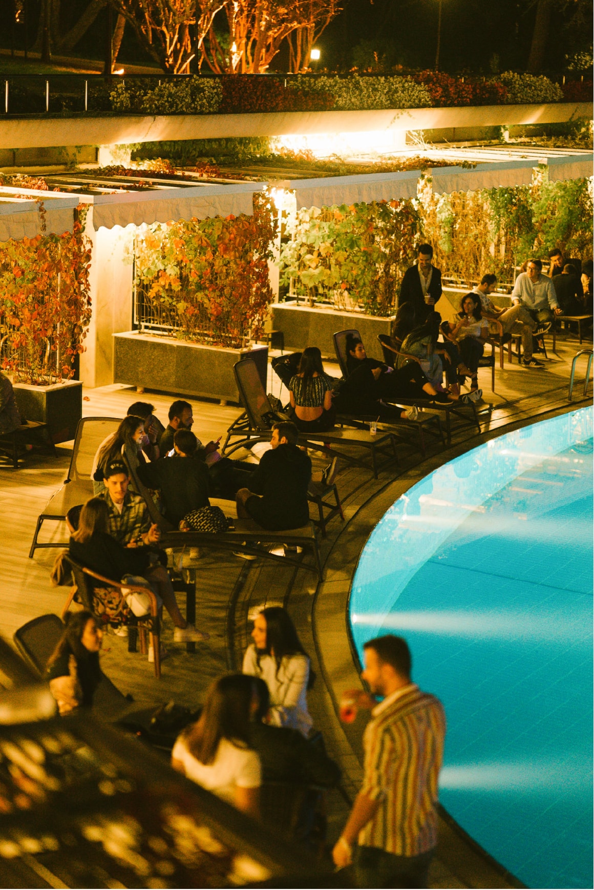 A KULÜP gathering arranged around the illuminated pool